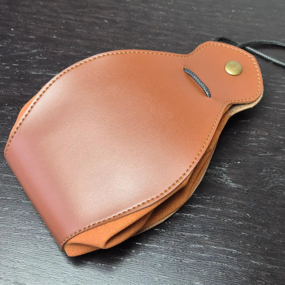 A brown leather dice bag with buttons and rope to tightly close it. Displayed on a black textured background