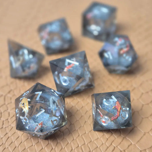 A set of clear grey tinted liquid core resin dice with koi fish inside filled with glitters on a beige textured surface