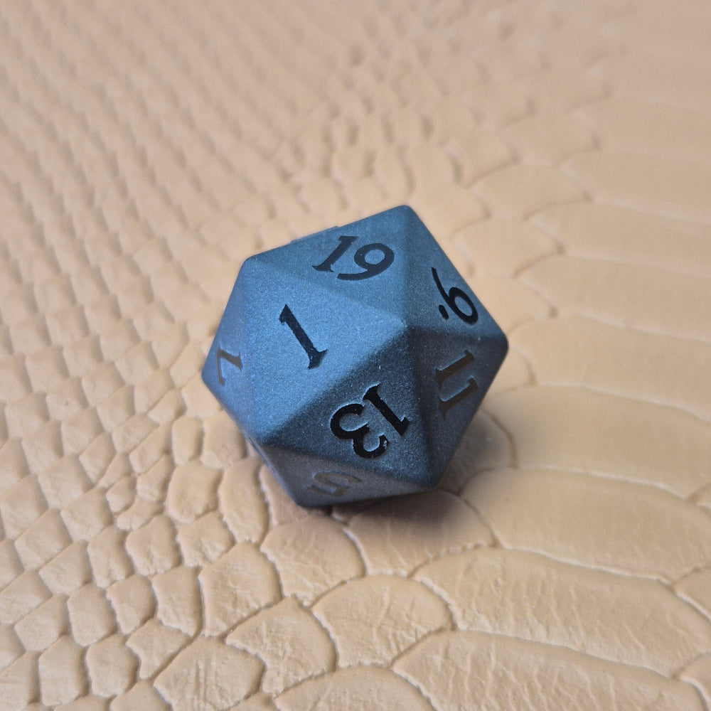 A set of matte black/ dark grey gemstone dice on a beige textured surface