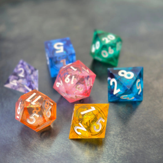 A set of rainbow coloured resin dice witch liquid core displayed on metal plate
