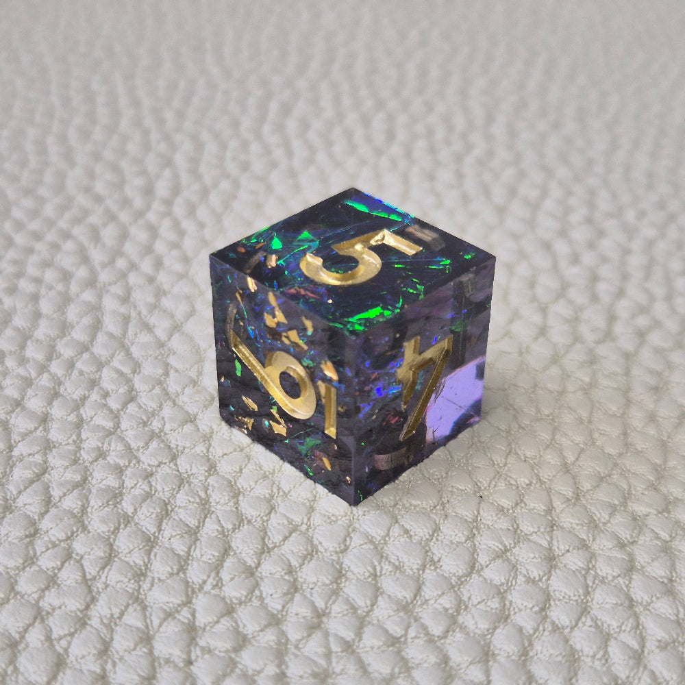 A set of blue sharp edge resin dice with green confetti inside on a white textured surface