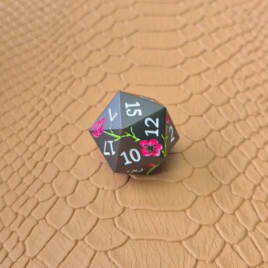 A black metal d20 dice on a brown dragon-like surface.