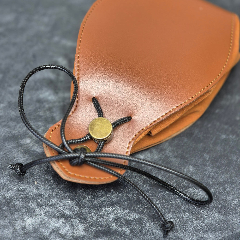 A brown leather dice bag with buttons and rope to tightly close it. Displayed on a black textured background
