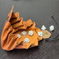 A brown leather dice bag with buttons and rope to tightly close it. Displayed on a black textured background