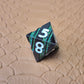 A set of black metal dice with shimmering green stripes and white numbering, displayed on a textured surface.