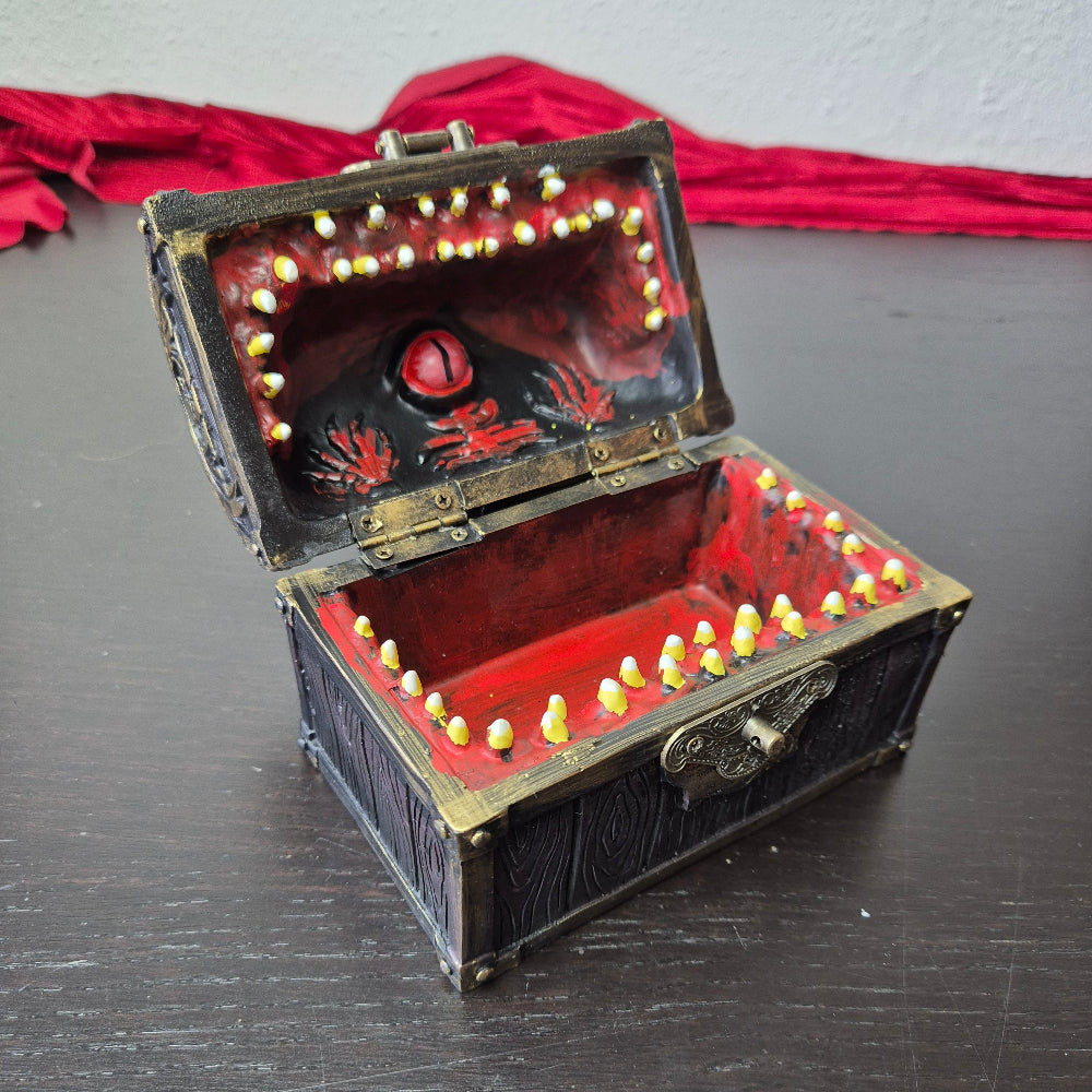 A brown ang gold mimic chest for dice storage With red and black painted mimic with teeth inside