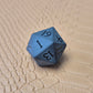 A set of matte black/ dark grey gemstone dice on a beige textured surface