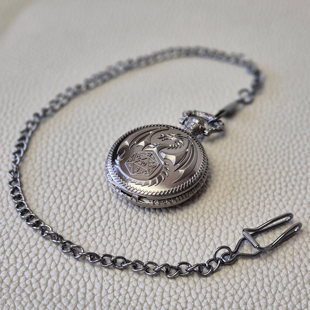 A silver coloured full metal pocket watch themed dice locket, with engraved backside and detailed dragon on the front. Contains full set of metal dice inside