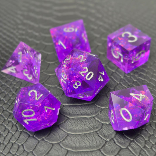 A set of sharp-edge purple resin dice and silver numbering, displayed on a black scale-textured surface.