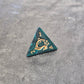 Acrylic D4 with emerald green swirls and antique gold arcane-style numbering, displayed on a textured dark surface.