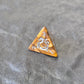 Gold acrylic D4 with ornate white fantasy-style numbers displayed on a stone surface, featuring a close-up of a d20.