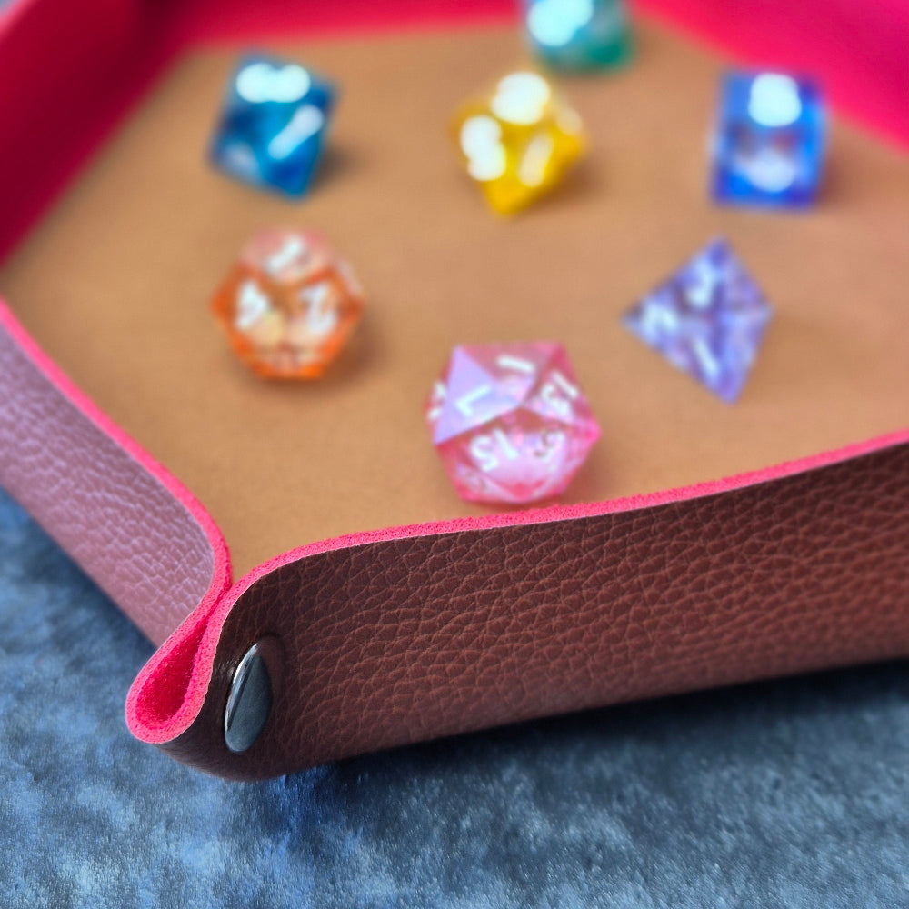 Foldable hexagon-shaped dice trays in red & brown shown open and filled with colorful polyhedral dice.